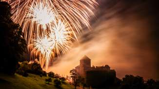 Vaduz Castle in Liechtenstein at night with large fireworks in the sky - atmospheric shot with light and fog