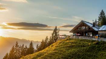 Gadafura hut on a sunny mountain meadow with a view of the mountains and sunset