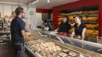 Sales room of a bakery with friendly staff, freshly baked bread and cakes in the foreground