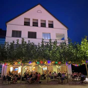 Atmospheric evening shot of St. Martins Pub with illuminated terrace and colorful fairy lights.
