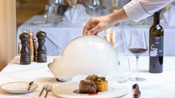 Gourmet dish served with meat and side dish, decoratively arranged under a white cloche in the elegant Alpspitz restaurant. Gourmet dish served with meat and side dish, decoratively arranged under a white cloche in the elegant Alpspitz restaurant.