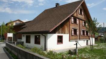 Historic Küefer-Martis-Huus with traditional wooden façade and red shutters in Ruggell, Liechtenstein.