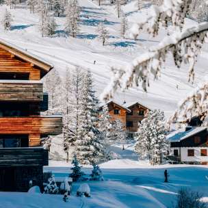 Cozy chalets in the winter sports resort of Malbun surrounded by snow-covered trees and ski slopes in the background