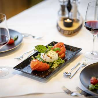 Fresh tomato and mozzarella salad with red wine on a laid table at the JUFA Hotel Malbun
