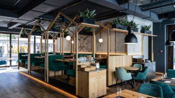 Modern restaurant with stylish wooden construction, green upholstered seats and creative room layout