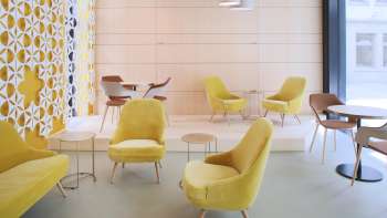 Modern café with stylish yellow armchairs, minimalist furnishings and bright windows