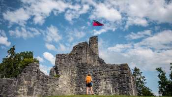 Hiker stands in front of the imposing ruins of Schellenberg Castle under a blue sky