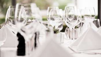 Close-up of several stacked wine glasses on a white table with luminous highlights.