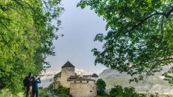 Two people are enjoying the view of Vaduz Castle from the walking path