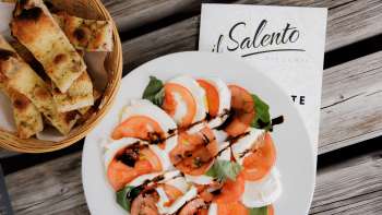 Fresh pizza with tomato sauce and rocket, served on a rustic wooden table