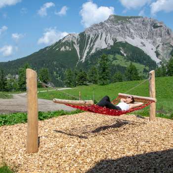 A woman lies relaxed on a hammock along the swinging path