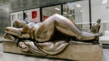 Voluptuous bronze female figure - Fernando Botero's work of art "Reclining Woman" as an eye-catcher in the city center.