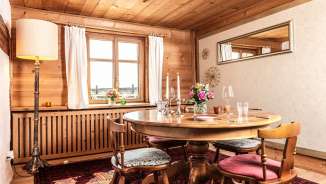Stylishly laid wooden table in a traditional Liechtenstein parlor with mountain views through the window
