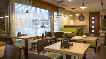 Modern bistro with a cozy ambience, wooden tables and stylish green benches