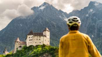 Mountain biker in yellow jacket looks down on Gutenberg Castle