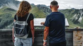 Couple looking at the mountain table on the terrace of the Sareis mountain inn