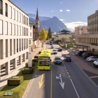 A LIEmobile bus drives through Vaduz against the backdrop of the Alps and modern architecture