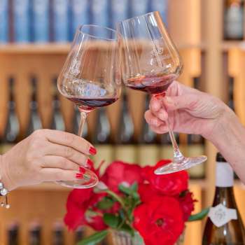 Two people toast with glasses of red wine in the Court Winery of the Prince of Liechtenstein