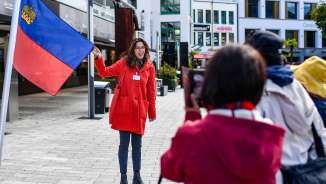 City guide presents the Liechtenstein flag during a guided tour through the center of Vaduz