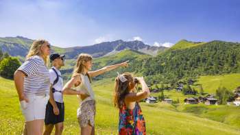 Family looking into the distance in the alpine landscape with a view of the mountains in summer