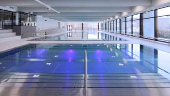 Modern indoor pool in Triesen with illuminated pool and large glass front.