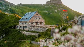 Close-up of the Pfälzerhütte hut the Liechtenstein flag at dusk.