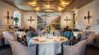 Round tables with wine glasses and candles in the elegant dining room of the Park Hotel Sonnenhof in Vaduz, Liechtenstein