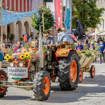 Festively decorated tractor with trailer at the Pradamee 2020 Alpine descent in Liechtenstein, surrounded by spectators