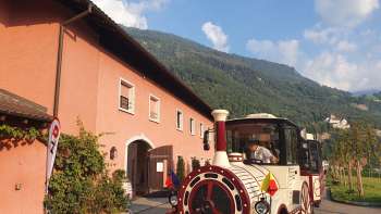 Citytrain in front of the historic Hofkellerei in Vaduz, ready to depart.