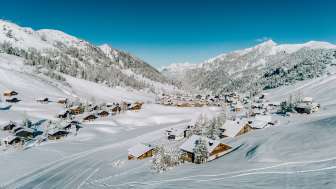 Aerial view of Malbun in winter with snow-covered wooden houses, nestled in the Liechtenstein Alpine landscape
