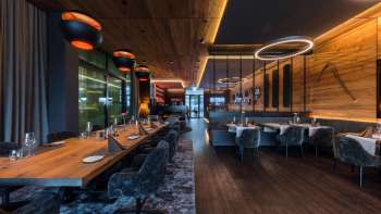 Elegant dining room with modern lighting elements and wood paneling on the walls.