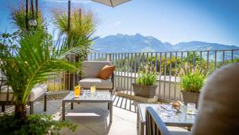 Sunny terrace with modern lounge furniture and Alpine panorama in the background