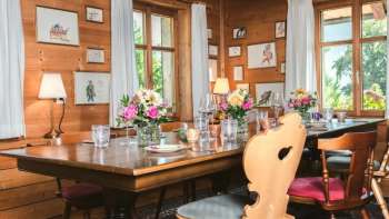 Inviting dining room with wooden ceiling, lovingly decorated table and bright window view