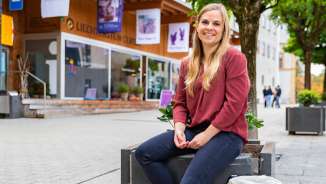 Young woman sits relaxed in front of the Liechtenstein Center in Vaduz and enjoys the trip to Vaduz