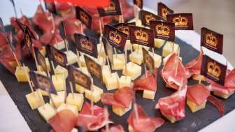 Appetizers with cheese cubes and air-dried ham, decorated with individually printed brand flags on a slate plate