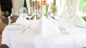 Festive table setting with white tablecloth and fresh tulip