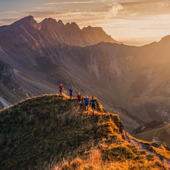 Group of trail runners on a mountain ridge near Malbun, Liechtenstein, in the warm light of the sunset with a view of the Alps