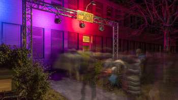 Entrance area of the Kleintheater Schlösslekeller at night with colorful lighting and audience