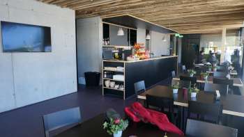 Modern dining room with dark tables, fresh flower arrangements and a rustic wooden roof