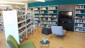 Cozy reading corner in the Liechtenstein National Library with armchairs and media wall between high bookshelves