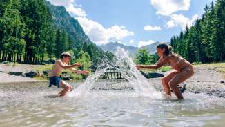 Children splash around in Gänglesee lake near Steg, surrounded by forests and mountains - experience nature and cool off in Liechtenstein