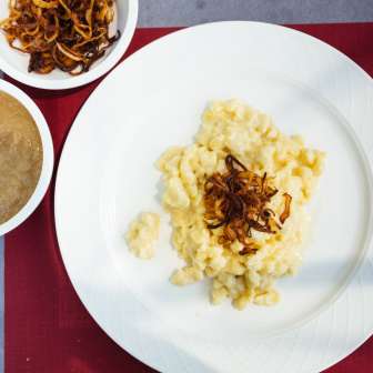 Traditional Käsknöpfle with fried onions and apple sauce from Liechtenstein on a white plate