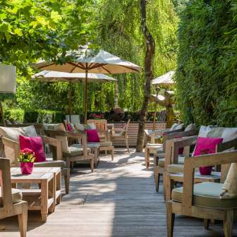 Comfortable seating area with cushions, plants and parasols on the terrace of the Park Hotel Sonnenhof in Vaduz, Liechtenstein