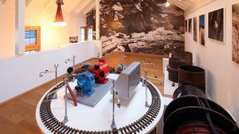 Model of a turbine on an exhibition platform in the Lawena Museum, with historical black and white photographs in the background.
