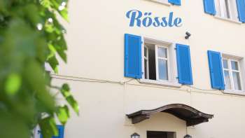 Exterior view of the Restaurant Rössle with blue shutters and cozy entrance area.
