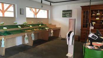 Self-service area of the Birkahoflädile with empty sales tables and green cash register - sustainable farm sales in Liechtenstein.