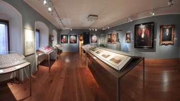 Panoramic view into an exhibition room of the NationalMuseum with historical paintings and showcases.