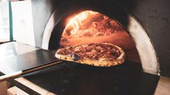 Pizza in a wood-fired oven with a golden-brown crust and crispy crust