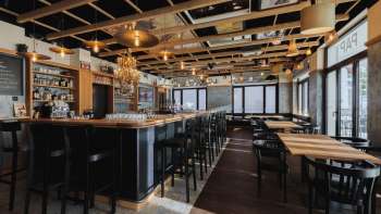 Bright interior of the St. Martins Pub with bar, wooden furniture and large window fronts