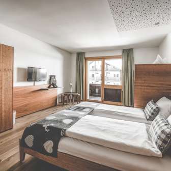 Cozy family room at the Hotel Gorfion in Malbun with wooden furniture, balcony and plenty of space for a relaxing vacation in the mountains.